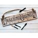 A handmade Christmas sign. Old time writing has been wood-burned onto a piece of reclaimed wood. Reindeer and holly are on either side. 